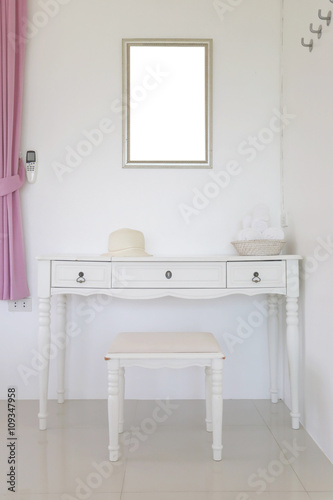 Vanity and have looking glass hanging on wall in the bedroom.