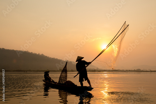 fisherman throwing fishing net during sunset