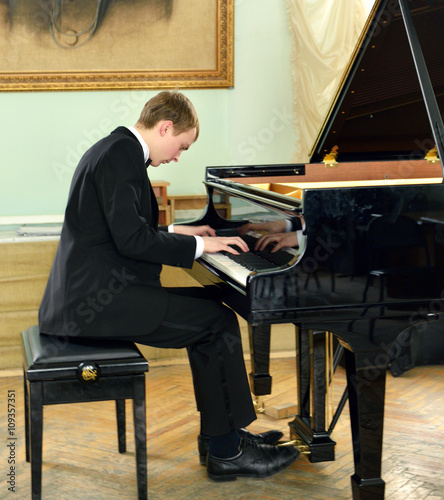 Canvastavla young pianist plays on black grand piano