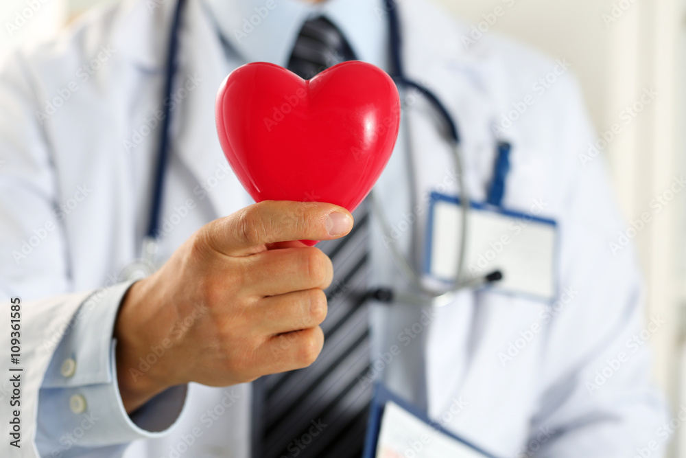 Male medicine doctor hands holding red toy heart Male medicine doctor hands holding red toy heart