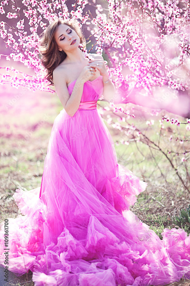 Adorable girl in blooming peach garden on sunny spring day
