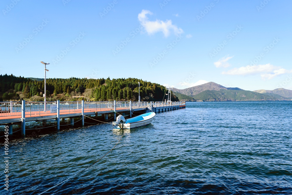 Small boat moored at pier with beautiful mountain and blue sky background.