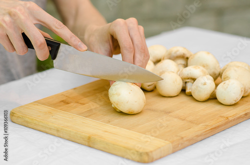 Mushrooms and Food theme: man preparing porcini mushrooms on a wooden board on a background of green grass in summer
