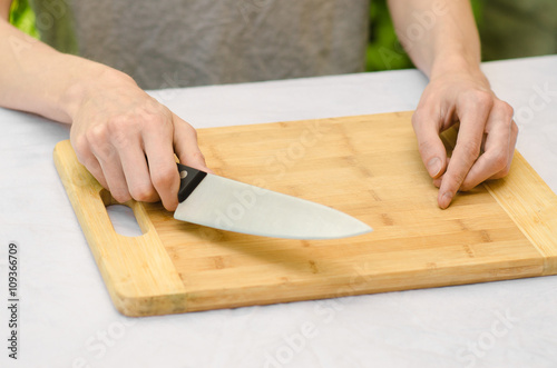 cooking theme: a man holding a knife next to a wooden cutting board on a background of green grass in summer