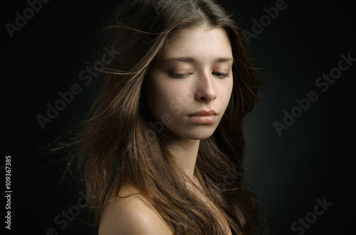 Dramatic portrait of a girl theme: portrait of a beautiful girl on a background in the studio