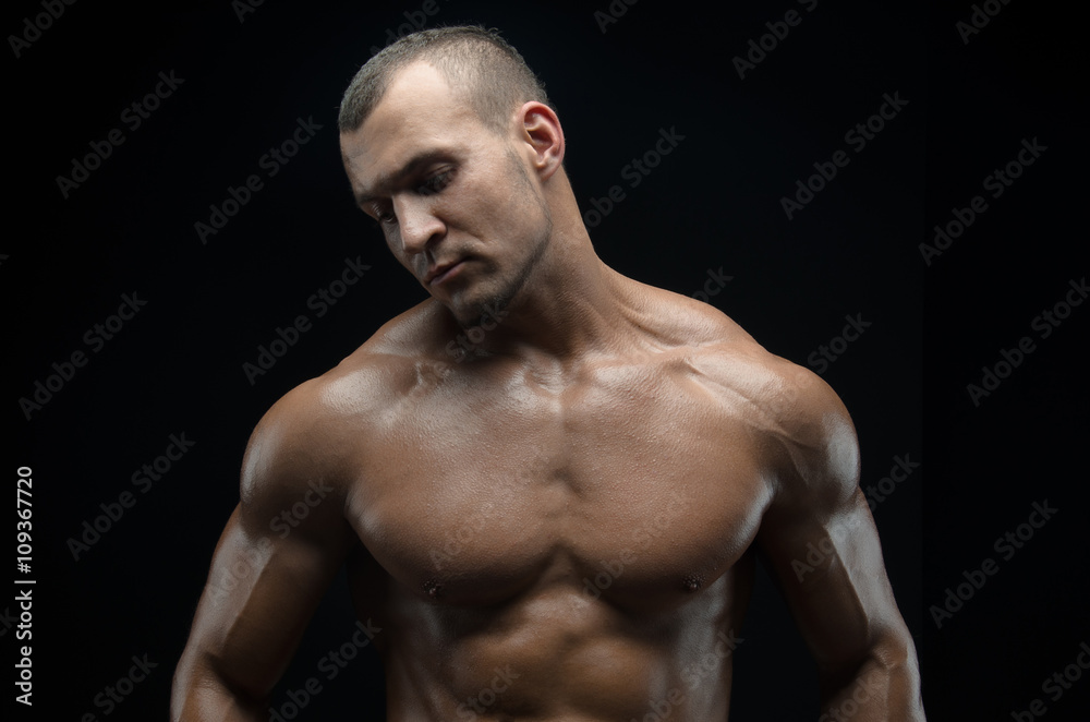 Bodybuilder and strip theme: beautiful with pumped muscles naked man posing in the studio on a dark background