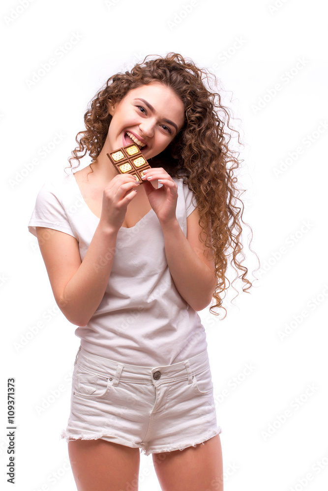 Portrait of a young beautiful girl with curly hair, holding a chocolate bar to enjoy the taste Portrait of a young beautiful girl with curly hair, holding a chocolate bar to enjoy the taste
