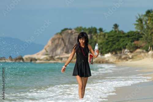 Young woman walking on the sea on a tropical beach