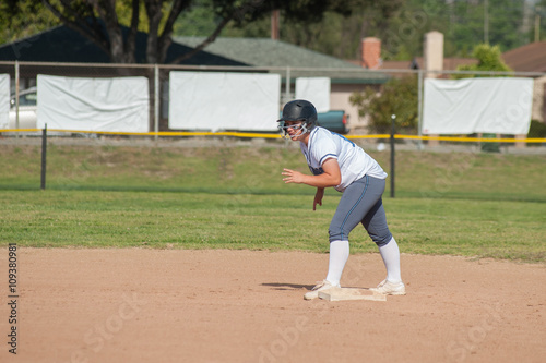 White uniform softball player on second base and ready to run.