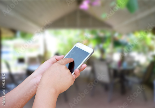 hand hold and touch screen smart phone, on blurred photo of coff