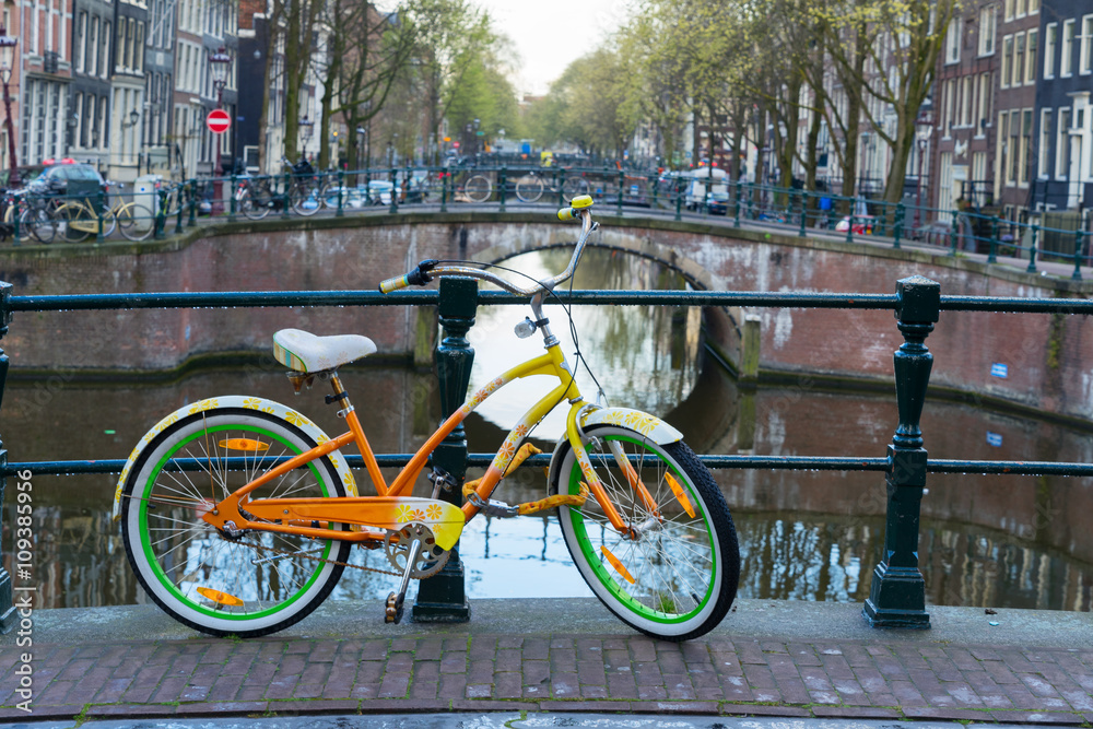 Orange  bicycle next to canal of Amsterdam 