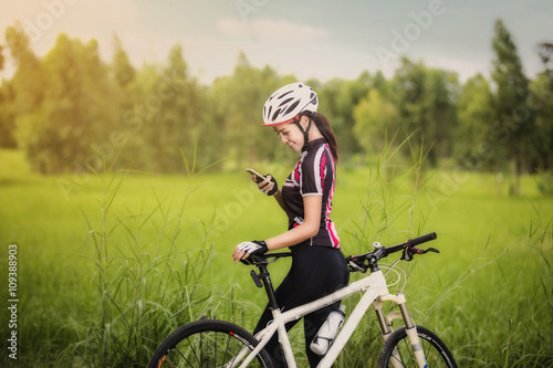 Woman cyclist relaxing and using smartphone