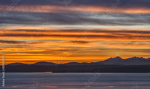 Beautiful Striped Orange Sunset with Olympic Mountains and Peninsula in Distance taken from Seattle, Washington