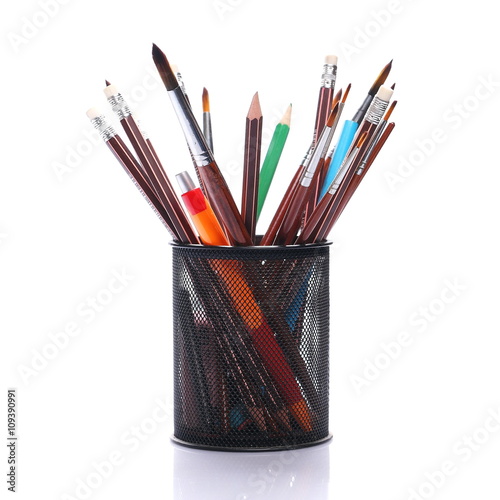 Paints brushes, pencils and wooden crayons isolated on white background