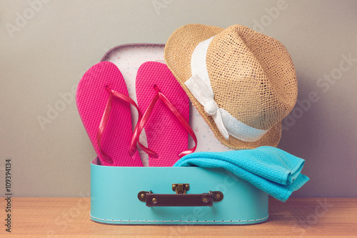 Summer holiday vacation concept with decorative suitcase and flip flops.