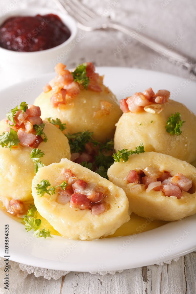 Potato dumplings stuffed with ham and onion close-up and lingonberry sauce. Vertical
