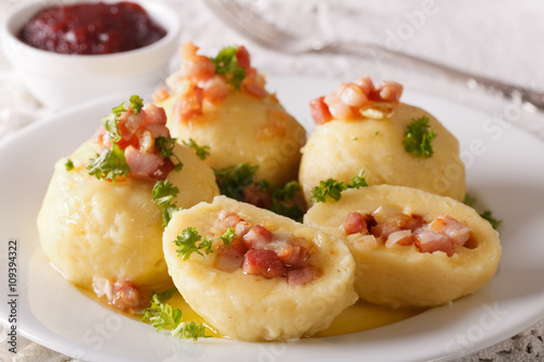 Potato dumplings with bacon, onion and ham close-up and berry sauce. horizontal 