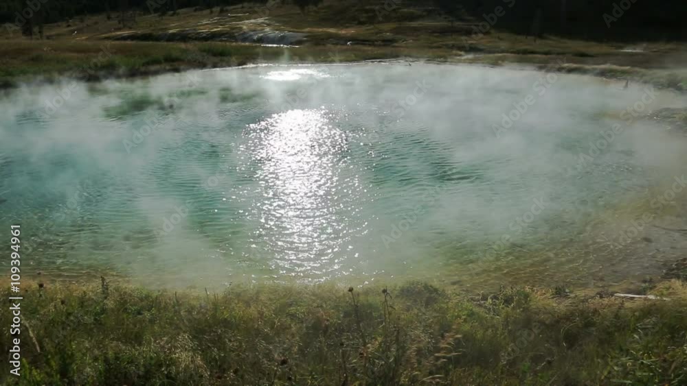 Mist blows from a vividly colorful geothermal hot spring in Yellowstone National Park. Mist blows from a vividly colorful geothermal hot spring in Yellowstone National Park.