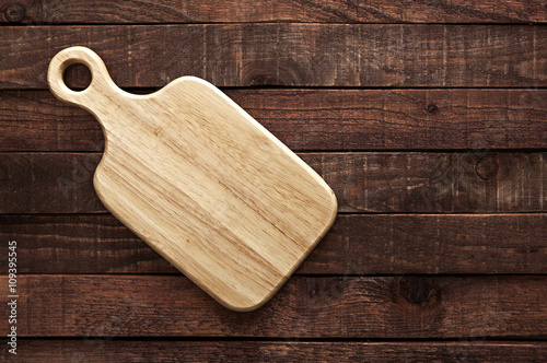 Cutting board on dark old wooden table. Top view