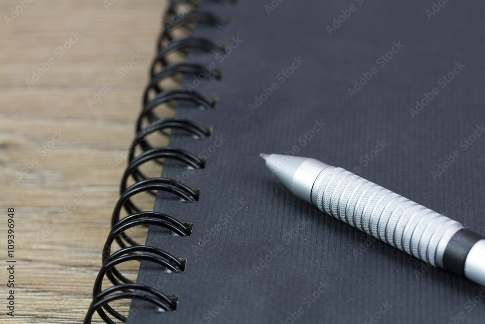 Black spiral bound notebook on wooden background Black spiral bound notebook on wooden background