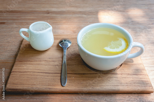 A cup of tea with honey and lemon on a wood table