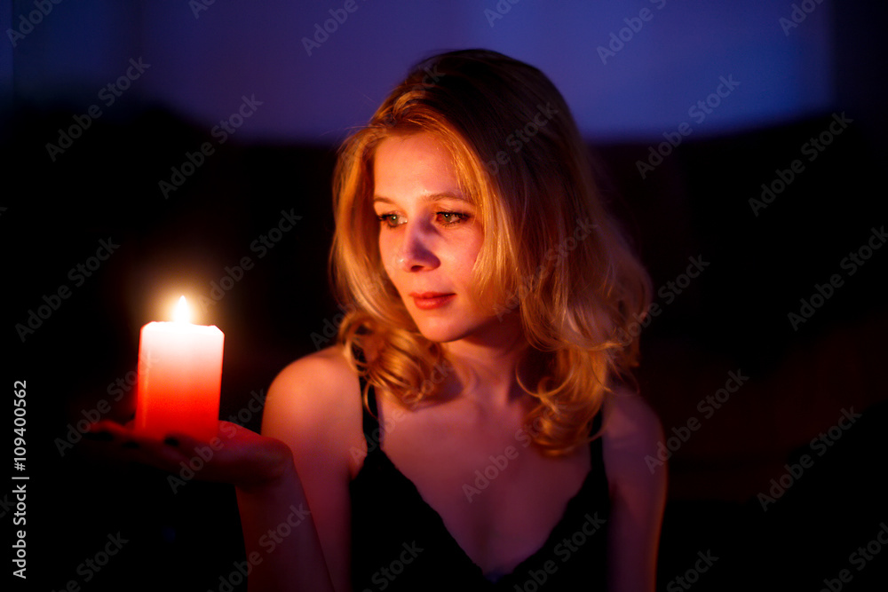 beautiful woman holds in the palm of a candle. young woman looking at candle beautiful woman holds in the palm of a candle. young woman looking at candle
