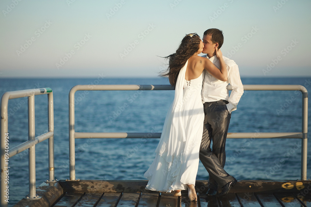 Gorgeous wedding couple kissing on pier under spray, splashes an