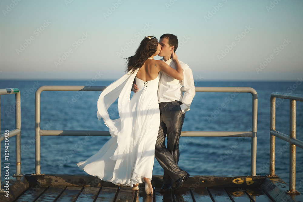 Gorgeous wedding couple kissing on pier under spray, splashes an