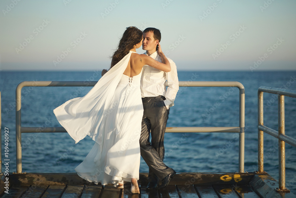 Gorgeous wedding couple kissing on pier under spray, splashes an