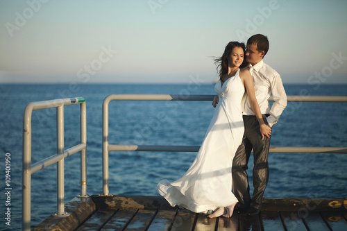 Gorgeous wedding couple standing on pier under spray, splashes a