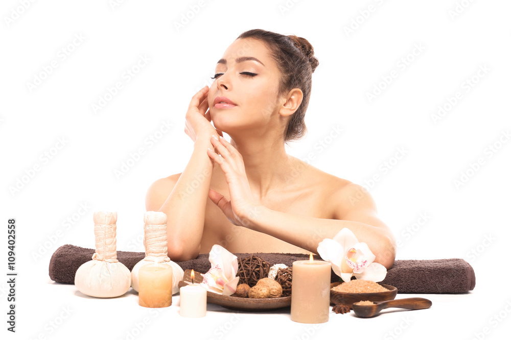 Beautiful young girl with aromatic candles and salt lying on brown towel, isolated on white Beautiful young girl with aromatic candles and salt lying on brown towel, isolated on white