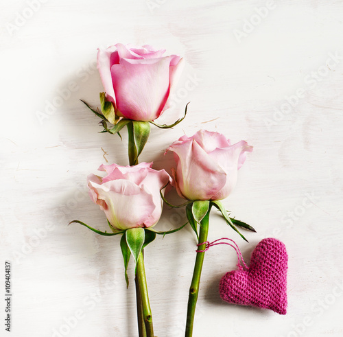 Pink roses and crochet heart on wooden background