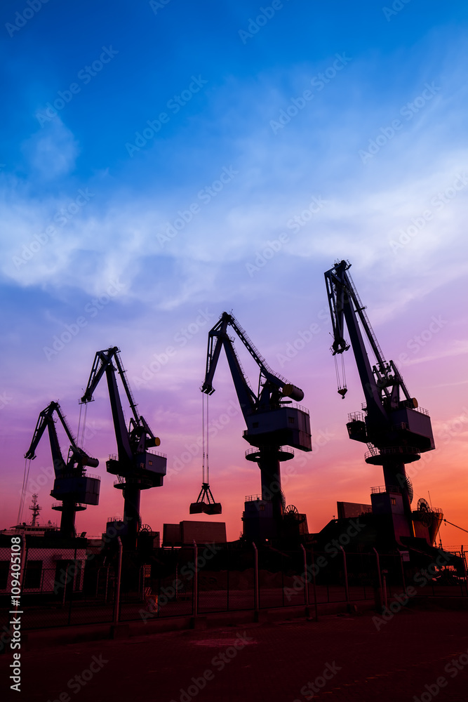 In the evening, the silhouette of port cranes In the evening, the silhouette of port cranes
