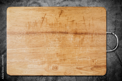 Fotografía Old scratched wooden cutting board, on dark concrete texture