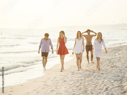 group of friends walking on the beach at sunse