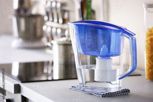 Water filter jug with napkin on kitchen table photo