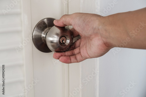 Close-up hand holding door knob, selective focus on knob