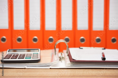 calculator and document on top  of open folder with documentatio