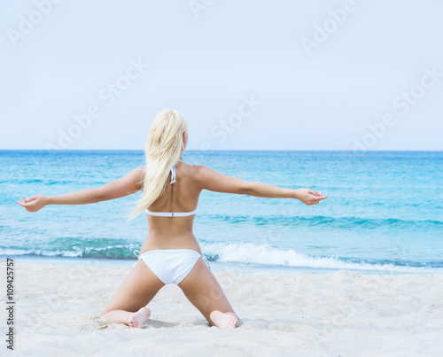 Young blond woman in a white swimsuit on the beach © Acronym