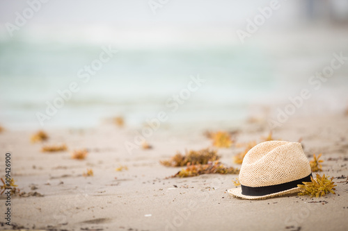 Nice straw hat laying on the sand. Beautiful ocean beach background. Outdoors. Vacation time. End of summer vacations. Dreaming of holidays by the sea. Traveling.
