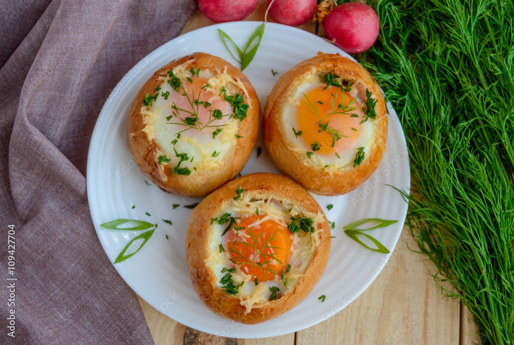 Eggs baked in a bun with ham, cheese and herbs. French breakfast.