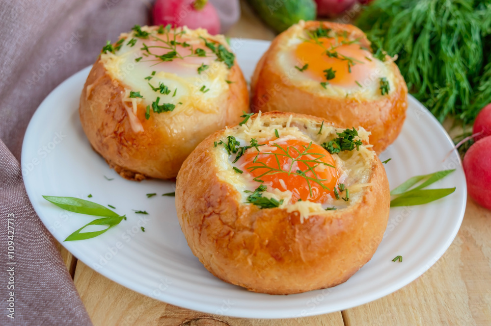Eggs baked in a bun with ham, cheese and herbs. French breakfast.