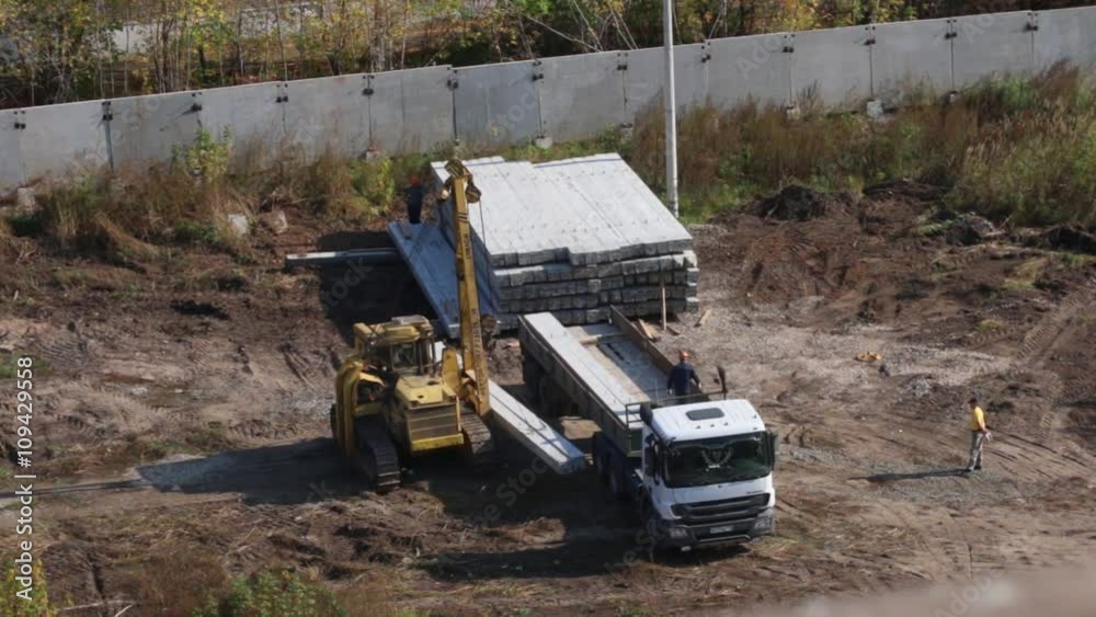 PERM, RUSSIA - SEP 28, 2015: Unloading concrete piles on construction site of largest developer Perm factory of silicate panels PERM, RUSSIA - SEP 28, 2015: Unloading concrete piles on construction site of largest developer Perm factory of silicate panels