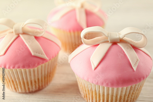 Tasty cupcakes with bow, on light background