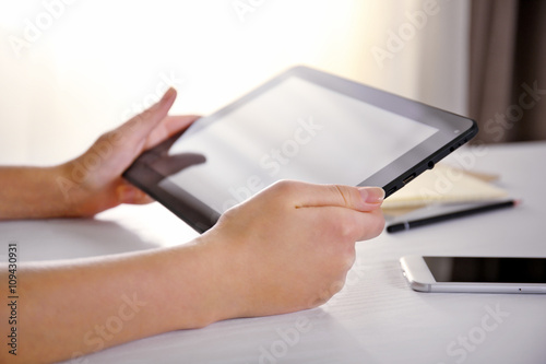 Mobile phone and female hands using modern tablet, indoors