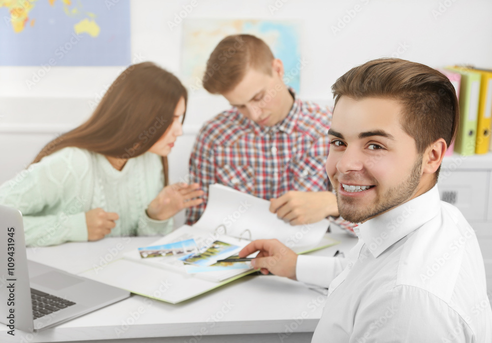 Agent offering vacation options for young couple in the office of travel company Agent offering vacation options for young couple in the office of travel company