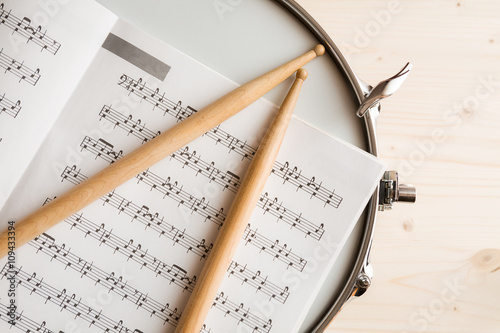 Music score drumsticks and drum tuner over a snare drum photo