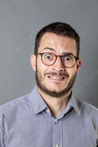 Fototapeta Naklejka Na Ścianę i Meble -  panicking young bearded businessman with eyeglasses grinding teeth
