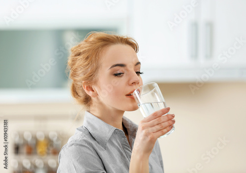 Young woman in the kitchen drinking water