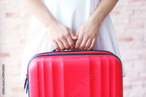 Woman in white dress holding a large red suitcase, close up